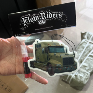 Ambientador con forma de camión empacado junto a un spray Flow Riders