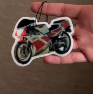 Ambientador con forma de motocicleta deportiva sostenido en la mano