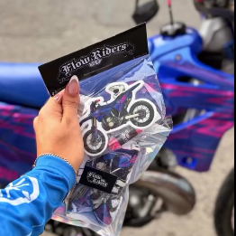 Set de ambientadores con diseños de motocicleta, sostenido junto a una moto real