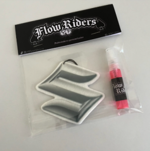 Ambientador con el logo de Suzuki empacado junto a un spray Flow Riders